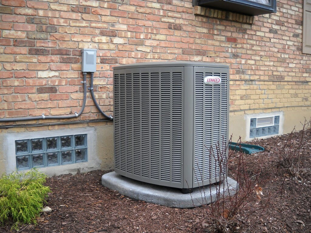 Air-conditioning condenser installed beside a brick home